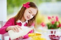 Cute little girl enjoying her breakfast at home. Pretty child eating corn flakes and raspberries and drinking milk before school. Royalty Free Stock Photo