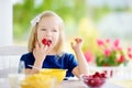 Cute little girl enjoying her breakfast at home. Pretty child eating corn flakes and raspberries and drinking milk before school. Royalty Free Stock Photo