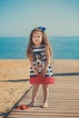 Cute little girl enjoying summer time on sea side beach happy playing with red star and tiny toy anchor on sand wearing nobby clot