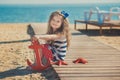 Cute little girl enjoying summer time on sea side beach happy playing with red star and tiny toy anchor on sand wearing nobby clot