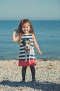 Cute little girl enjoying summer time on sea side beach happy playing with red star and tiny toy anchor on sand wearing nobby clot