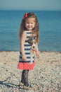 Cute little girl enjoying summer time on sea side beach happy playing with red star and tiny toy anchor on sand wearing nobby clot