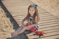 Cute little girl enjoying summer time on sea side beach happy playing with red star and tiny toy anchor on sand wearing nobby clot