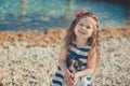 Cute little girl enjoying summer time on sea side beach happy playing with red star and tiny toy anchor on sand wearing nobby clot