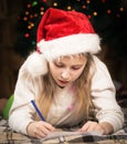 A cute little girl with enthusiasm writes a letter to Santa