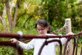 Cute little girl in eyeglasses climbing on a rope bridge Royalty Free Stock Photo