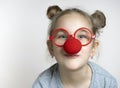 Cute little girl in eyeglasses and clown nose studio portrait