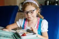 Cute Little Girl with Eyeglasses Eating Sandwich and Fruits during Break between Classes. Healthy Unhealthy Food for Kid Royalty Free Stock Photo