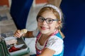 Cute Little Girl with Eyeglasses Eating Sandwich and Fruits during Break between Classes. Healthy Unhealthy Food for Kid Royalty Free Stock Photo