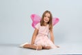 Cute little girl in fairy costume with pink wings and magic wand on light background Royalty Free Stock Photo