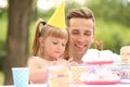 Cute little girl with father eating cake at birthday party outdoors Royalty Free Stock Photo