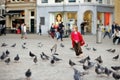 Cute little girl feeding and chasing birds on Dam Square in Amsterdam on summer day