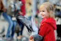 Cute little girl feeding and chasing birds on Dam Square in Amsterdam on summer day