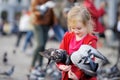 Cute little girl feeding and chasing birds on Dam Square in Amsterdam on summer day