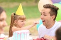 Cute little girl feeding her father with cake at birthday party outdoors Royalty Free Stock Photo