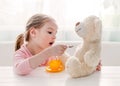 Cute little girl feeding toy teddy bear Royalty Free Stock Photo