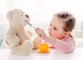 Cute little girl feeding toy teddy bear Royalty Free Stock Photo