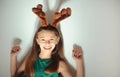 Cute little girl in festive green dress with a deer ears posing on light background. Royalty Free Stock Photo