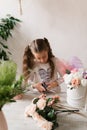 little girl florist collects a bouquet of flowers at the table