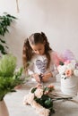 little girl florist collects a bouquet of flowers at the table