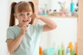 Cute little girl flossing her teeth in bathroom Royalty Free Stock Photo