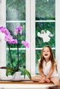 Cute little girl with flower sitting on windowsill of new pvc wi Royalty Free Stock Photo