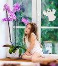 Cute little girl with flower sitting on windowsill of new pvc wi Royalty Free Stock Photo