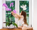 Cute little girl with flower sitting on windowsill of new pvc wi Royalty Free Stock Photo