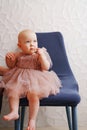 Cute little girl in a fluffy fancy pink dress sitting on a blue chair. Royalty Free Stock Photo