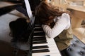 Cute little girl folds her hands and hid her face, feeling sadness, having difficulties or forced to learn playing piano Royalty Free Stock Photo