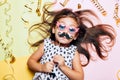 Cute little girl in funny glasses with paper mustache.