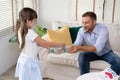 Cute little girl is giving her father gift box at home in the living room. Happy Father`s day. Family holiday, vacation.