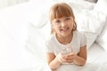 Cute little girl with glass of fresh water sitting in bed at home. Royalty Free Stock Photo