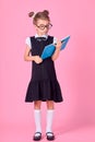 Cute little girl with glasses and books on pink background, space for text. Reading concept