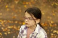 Cute little girl in glasses and plaid shirt in autumn park Royalty Free Stock Photo