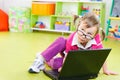 Cute little girl in glasses with laptop on floor Royalty Free Stock Photo