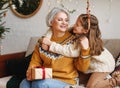 Little girl granddaughter giving Christmas gift box to smiling grandmother during winter holidays Royalty Free Stock Photo