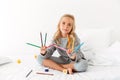 Cute little girl in gray pajamas showing her colorful pencils, l Royalty Free Stock Photo