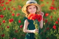 Cute little girl in green dress and straw hat with a bouquet of poppies posing at field of poppies in her hands on Royalty Free Stock Photo