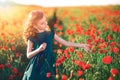 Cute little girl in green dress and straw hat posing at field of poppies on summer sunset Royalty Free Stock Photo