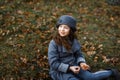 A cute little girl in grey coat and gray hat near the thick old oak in the oak wood at the sunset Royalty Free Stock Photo