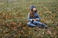 A cute little girl in grey coat and gray hat near the thick old oak in the oak wood at the sunset Royalty Free Stock Photo