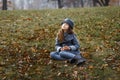 A cute little girl in grey coat and gray hat near the thick old oak in the oak wood at the sunset Royalty Free Stock Photo