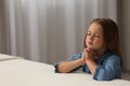 Cute little girl with hands clasped together saying bedtime prayer in bedroom. Space for text Royalty Free Stock Photo