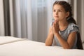 Cute little girl with hands clasped together saying bedtime prayer at home. Space for text Royalty Free Stock Photo