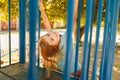 A cute little girl hangs upside down on a children& x27;s slide Royalty Free Stock Photo