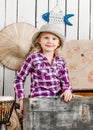 Cute little girl in hat sitting in chest