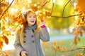 Cute little girl having fun on beautiful autumn day. Happy child playing in autumn park. Kid gathering yellow fall foliage. Royalty Free Stock Photo