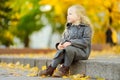 Cute little girl having fun on beautiful autumn day. Happy child playing in autumn park. Kid gathering yellow fall foliage. Royalty Free Stock Photo