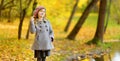 Cute little girl having fun on beautiful autumn day. Happy child playing in autumn park. Kid gathering yellow fall foliage. Royalty Free Stock Photo